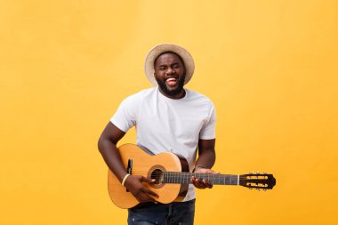 Akustik gitar üzerinde sarı arka plan izole çalmaya gitarist yakışıklı Afro-Amerikan retro tarz.