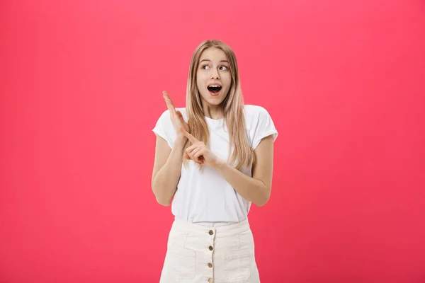 Jolie jeune femme portant un t-shirt blanc pointe un doigt isolé sur fond rose — Photo