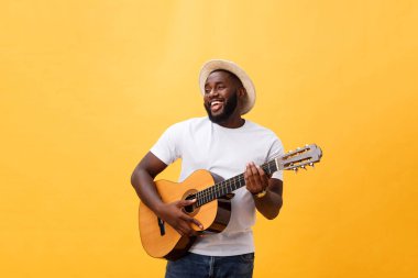 Akustik gitar üzerinde sarı arka plan izole çalmaya gitarist yakışıklı Afro-Amerikan retro tarz.
