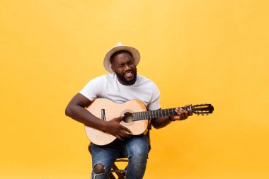 Akustik gitar üzerinde sarı arka plan izole çalmaya gitarist yakışıklı Afro-Amerikan retro tarz