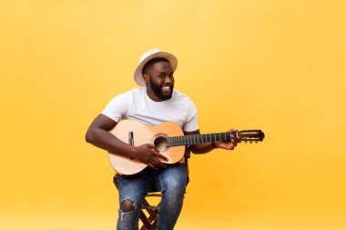 Akustik gitar üzerinde sarı arka plan izole çalmaya gitarist yakışıklı Afro-Amerikan retro tarz.
