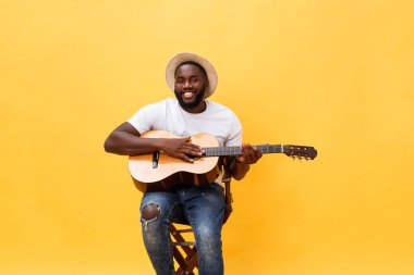 Akustik gitar üzerinde sarı arka plan izole çalmaya gitarist yakışıklı Afro-Amerikan retro tarz.