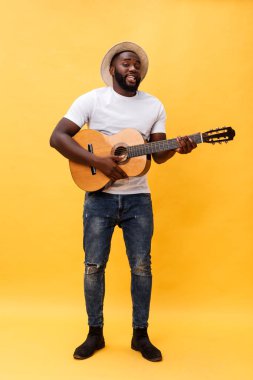 Akustik gitar üzerinde sarı arka plan izole çalmaya gitarist yakışıklı Afro-Amerikan retro tarz