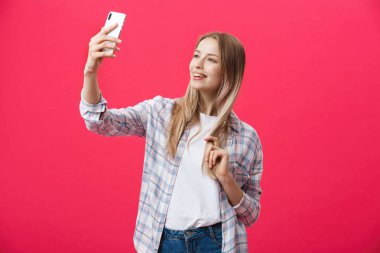 Sevimli genç kadın beyaz şapkalı seyahat ve Parlatıcı pembe arka plan üzerinde izole smartphone ön kamera poz üzerinde selfie al