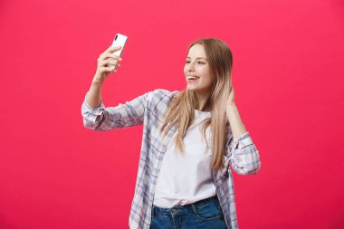 Sevimli genç kadın beyaz şapkalı seyahat ve Parlatıcı pembe arka plan üzerinde izole smartphone ön kamera poz üzerinde selfie al