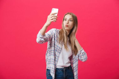 Sevimli genç kadın beyaz şapkalı seyahat ve Parlatıcı pembe arka plan üzerinde izole smartphone ön kamera poz üzerinde selfie al