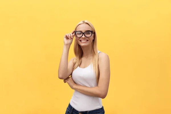 Happy stylish modern woman with modern shaped sunglasses laughing looking at you camera isolated on yellow background. Happiness concept