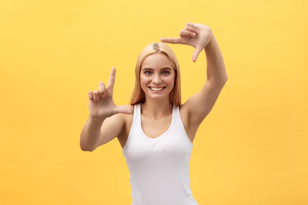 Lycklig kvinna gör ram med fingrar isolerade på en gul bakgrund. — Stockfoto