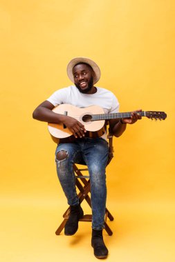 Tam uzunlukta fotoğraf heyecanlı sanatsal adamın onun gitar çalmak. Sarı arka plan üzerinde izole.