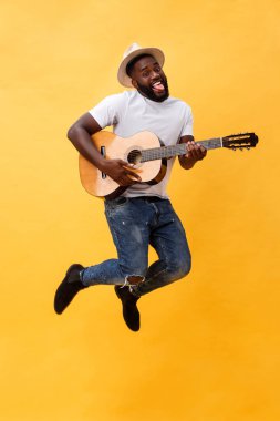 Tam uzunlukta fotoğraf heyecanlı sanatsal adamın onun gitar çalmak. Sarı arka plan üzerinde izole.