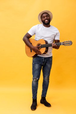Tam uzunlukta fotoğraf heyecanlı sanatsal adamın onun gitar çalmak. Sarı arka plan üzerinde izole.