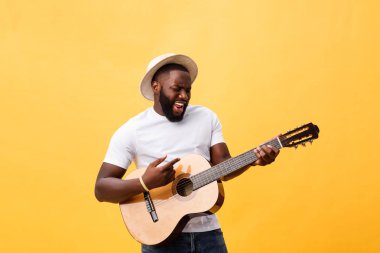 Kot pantolon ve beyaz kolsuz bluz giyen gitar, çalmak kas siyah adam. Sarı arka plan üzerinde izole.