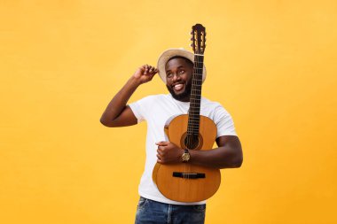 Kot pantolon ve beyaz kolsuz bluz giyen gitar, çalmak kas siyah adam. Sarı arka plan üzerinde izole.