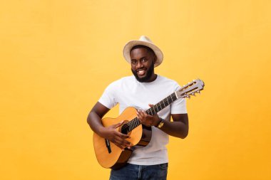 Kot pantolon ve beyaz kolsuz bluz giyen gitar, çalmak kas siyah adam. Sarı arka plan üzerinde izole.