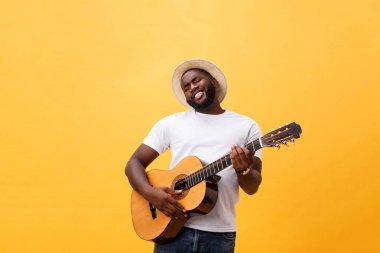 Kot pantolon ve beyaz kolsuz bluz giyen gitar, çalmak kas siyah adam. Sarı arka plan üzerinde izole.