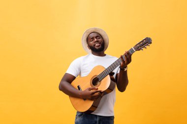 Kot pantolon ve beyaz kolsuz bluz giyen gitar, çalmak kas siyah adam. Sarı arka plan üzerinde izole.