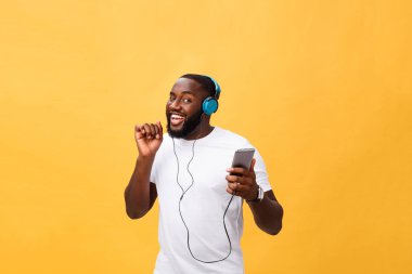 Kulaklıklar ile Afrika kökenli Amerikalı adam dinlemek ve müzik ile dans. Sarı arka plan üzerinde izole