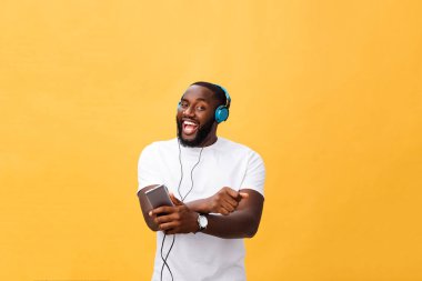 Kulaklıklar ile Afrika kökenli Amerikalı adam dinlemek ve müzik ile dans. Sarı arka plan üzerinde izole