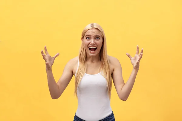 Retrato de una mujer enojada irritada con las manos levantadas gritando a la cámara aislada sobre fondo amarillo — Foto de Stock