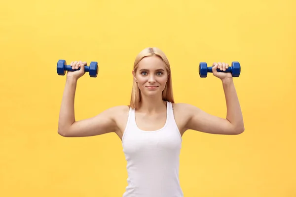 Fitness woman lifting weights smiling happy isolated on yellow background. Fit sporty Caucasian female fitness model.