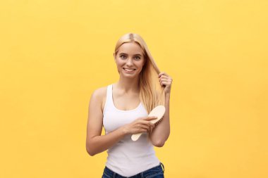 Saçlarını tarayan, kameraya bakıp gülümseyen güzel bir genç kadının portresi..