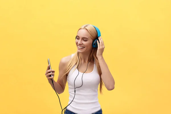 Lifestyle Portrait d'une femme heureuse écoutant de la musique dans des écouteurs isolés sur un fond jaune — Photo