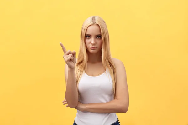 Vrouw toont wijzen op gele achtergrond. Zeer fris en energiek mooi jong meisje glimlachend gelukkig presenteren op gele achtergrond. — Stockfoto