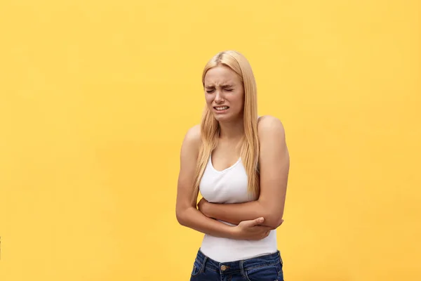 woman stomach ache because of gastritis or menstruation that are sign of stomach trouble with yellow background tone