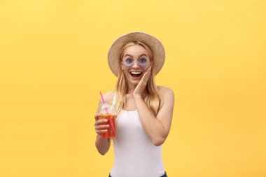 Muhteşem kadın bardak suyu izole sarı arka plan üzerinde tutarak beyaz t-shirt giyen güneş gözlüğü