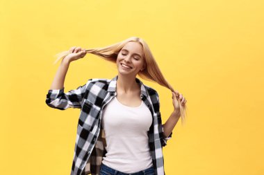 Mutlu bir şekilde gülümseyerek, içeride eğleniyor, uzun düz saçlı oynayan güzel çok çekici sarışın genç kadın. Güzel kız kameraya neşeli gülümseme ile seyir hayat bayram