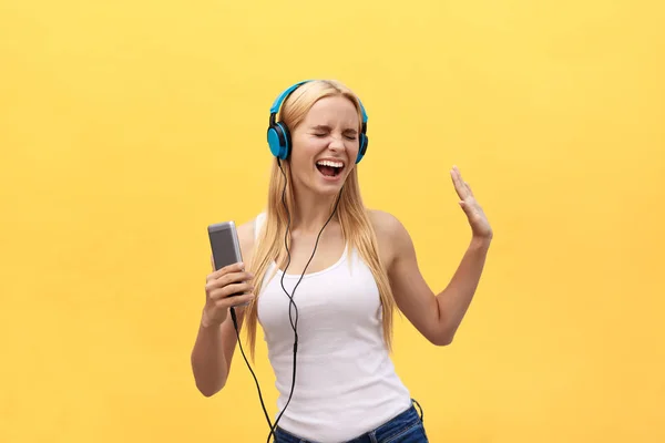 Stile di vita Ritratto di una donna felice che ascolta musica in cuffie isolate su uno sfondo giallo — Foto Stock
