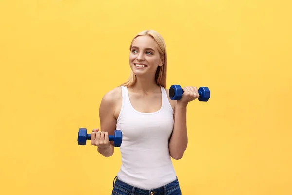 Fitness woman lifting weights smiling happy isolated on yellow background. Fit sporty Caucasian female fitness model.