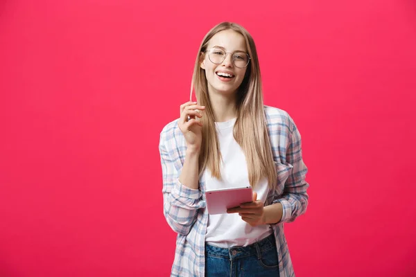 Porträtt av en skrattande kvinna som använder tablet PC isolerad på en rosa bakgrund och tittar på kameran — Stockfoto