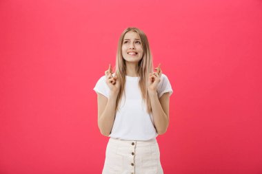 İyi şanslar pembe arka plan üzerinde izole için dua tutan bir gülümseyen casual kız portresi