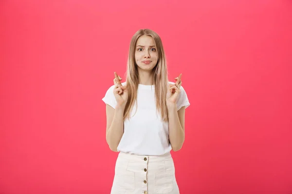 Portrait d'une fille décontractée souriante tenant les doigts croisés pour la bonne chance isolé sur fond rose — Photo