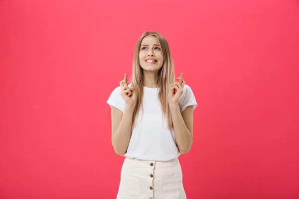 Portrait d'une fille décontractée souriante tenant les doigts croisés pour la bonne chance isolé sur fond rose — Photo