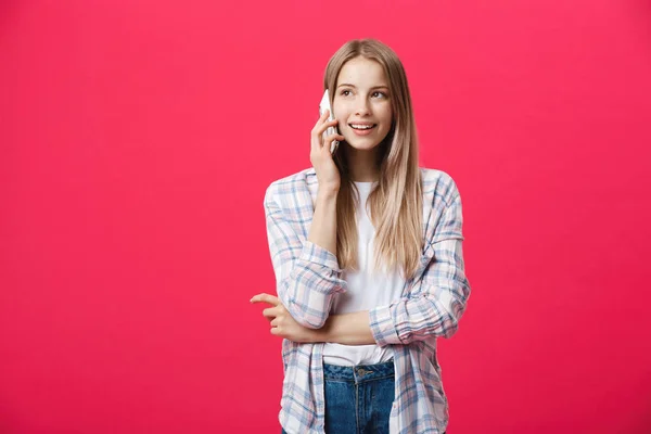 Веселая молодая женщина разговаривает по мобильному телефону изолированы на розовом фоне — стоковое фото