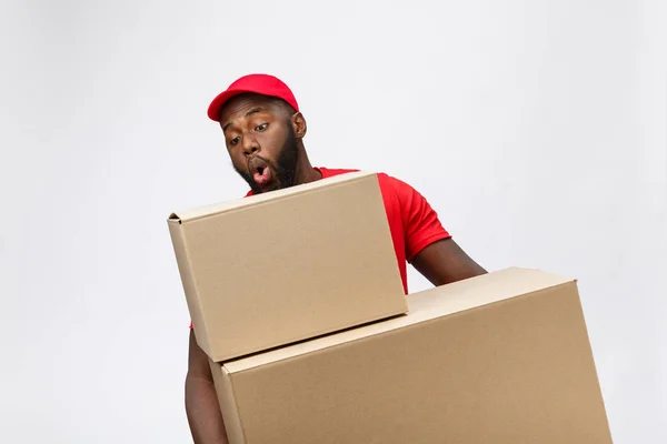 Retrato da entrega homem americano africano em camisa vermelha. ele levantando caixas de peso pesado contra ter um isolado no fundo branco . — Fotografia de Stock