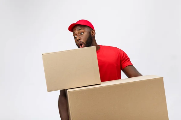 Egy afro-amerikai férfi vörös ingben. ő emel nehéz súlyú dobozok ellen, hogy egy elszigetelt a fehér háttér. — Stock Fotó