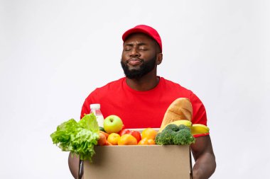 Teslimat Konsepti - Yakışıklı Afro-Amerikalı teslimatçı marketten bir paket yiyecek ve içecek taşıyor. Grey Stüdyo Arkaplanı 'nda izole edilmiş. Boşluğu Kopyala