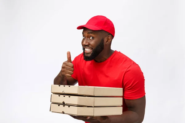 Conceito de entrega - Retrato de entregador afro-americano feliz segurando um pacote de caixa de pizza e mostrando os polegares para cima. Isolado no estúdio Grey Background. Espaço de cópia — Fotografia de Stock