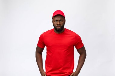 Teslimat Konsepti - Ciddi Afro-Amerikan teslimatçının portresi aptalca agresif bir ifade sergiliyor ve mutsuz. Grey Stüdyo Arkaplanı 'nda izole edilmiş. Boşluğu Kopyala.