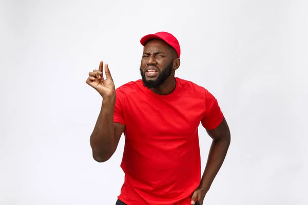 Delivery Concept - Portret van Serieuze Afro-Amerikaanse bezorger met domme agressieve expressie en ongelukkig. Geïsoleerd op Grey Studio Achtergrond. Kopieer ruimte.. — Stockfoto