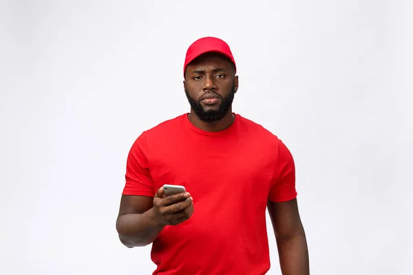 Africano americano serio repartidor de llamadas telefónicas en su teléfono móvil con una expresión seria aislado en blanco — Foto de Stock