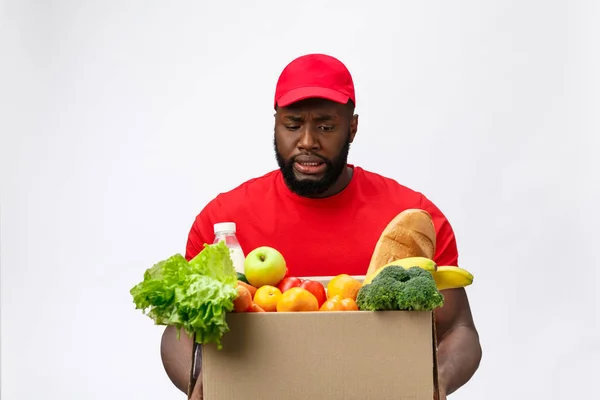 Retrato da entrega homem americano africano em camisa vermelha. ele levantando caixas de supermercado de peso pesado contra ter um isolado no fundo branco . — Fotografia de Stock