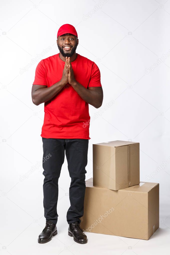 Handsome Afro American delivery man with hand praying isolated over grey background.