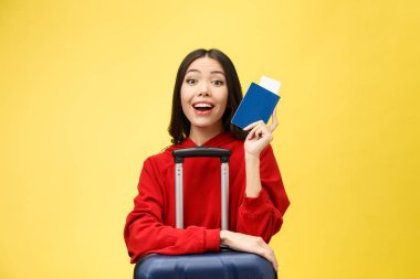Kadın seyahati. Sarı arka planda pasaportu ve bavulu olan güzel Asyalı kadın gezgin.