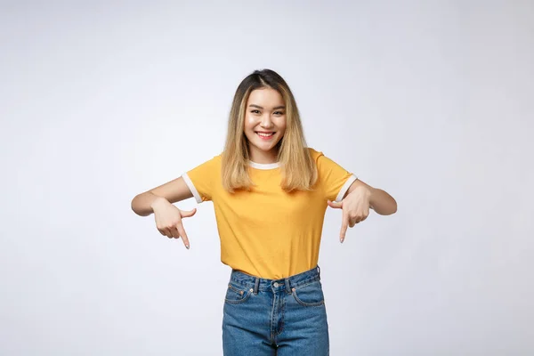 Hermosa mujer asiática joven apuntan hacia abajo al espacio en blanco sobre fondo gris . — Foto de Stock