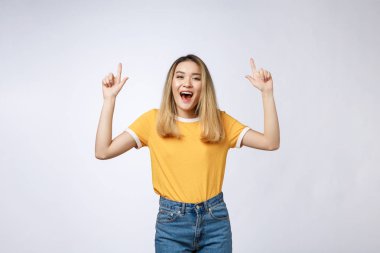 Güzel genç Asyalı kadın beyaz arka plan üzerinde neşeli ifade ile parmağıyla yukarıyı.