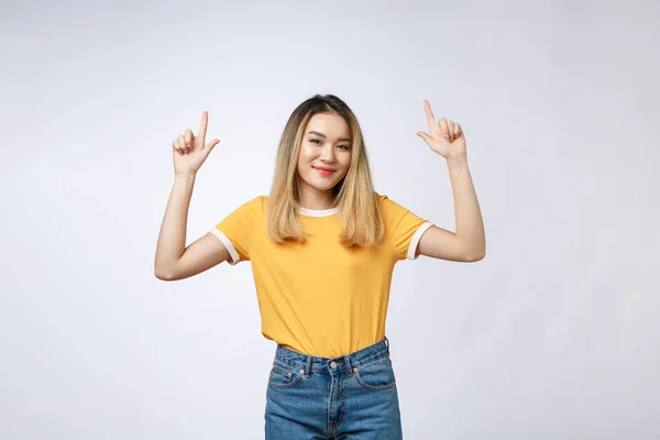 Güzel genç Asyalı kadın beyaz arka plan üzerinde neşeli ifade ile parmağıyla yukarıyı. — Stok fotoğraf